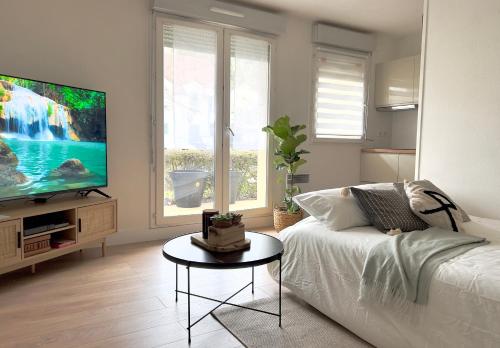 a living room with a white couch and a flat screen tv at La Voulzie Appartement - Proche centre avec parking privé in Provins
