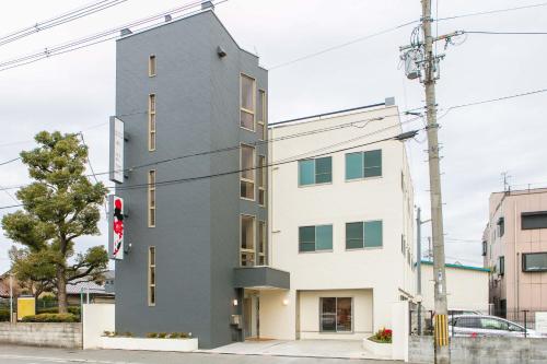 un edificio gris en una calle de la ciudad con un semáforo en GUEST House彩, en Osaka