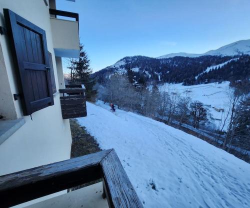 une vue d'une colline enneigée avec une porte dans l'établissement Appartement 4/6 le lioran, à Laveissière
