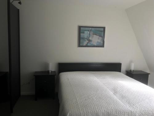 1 dormitorio blanco con 1 cama y 2 mesitas de noche en Appartement De Braam, en Emmer-Erfscheidenveen