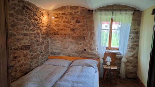 ein Schlafzimmer mit einem Bett und einer Steinmauer in der Unterkunft Old Style Cottage in Horní Paseka