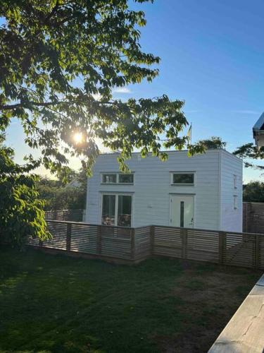 ein weißes Haus mit einem Holzzaun im Hof in der Unterkunft Attefallshus in Falkenberg