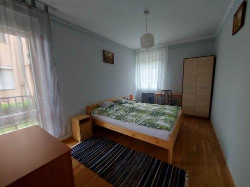 a bedroom with a bed and a large window at Balaton apartman in Balatonboglár