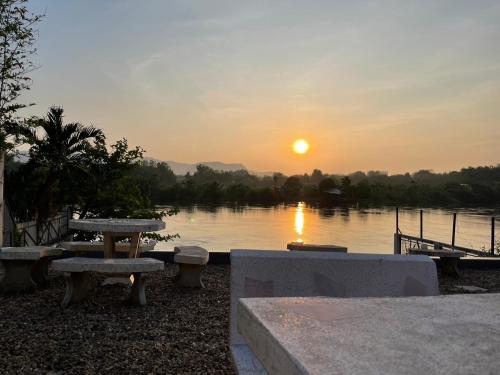 a sunset over a lake with a picnic table at Tara Kan Resort in Ban Nong Hin