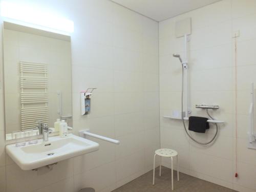 a white bathroom with a sink and a shower at Barrierefreies Apartment Ursulinenhof in Oberried
