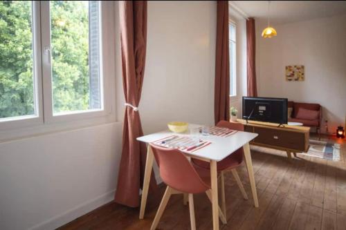 ein Wohnzimmer mit einem Tisch, Stühlen und einem Schreibtisch in der Unterkunft L’appartement Le Mer’Ville in Saint-Nazaire