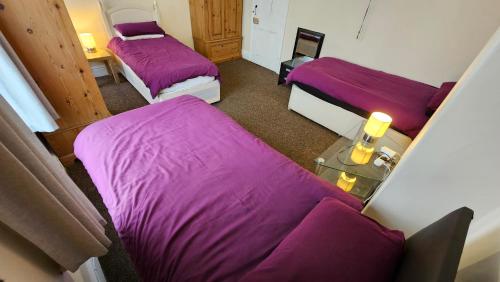 two beds in a room with purple sheets at Sherwood Terrace 3 Bedroom 1 Double Bed 4 Single Beds Entire Property Contractors Welcome in Boston