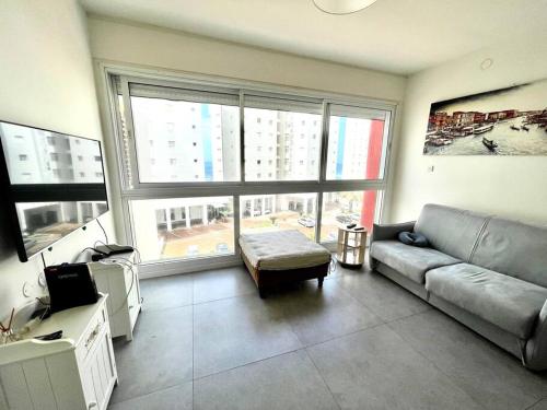 een woonkamer met een bank en een groot raam bij SVW Apartment on the Beach in Netanya