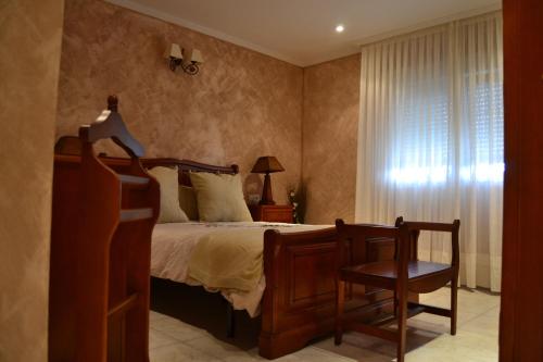 a bedroom with a bed and a chair and a window at La Gala in Olmedo
