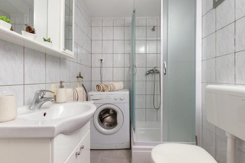 a white bathroom with a washing machine and a sink at Bernard Old Town Apartment in Split