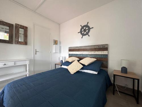 Un dormitorio con una cama azul y un reloj en la pared en Appartement La Petite Maison, en Le Grau-du-Roi