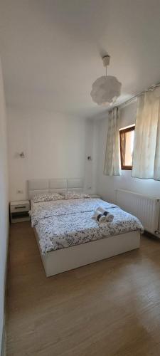 a white bedroom with a bed and a window at Golden Stars Malca in Arad