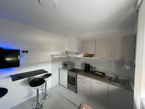 una cucina con armadi bianchi, lavandino e bancone di Apartman Paola - massage chair- 0-24 self check IN OUT- Županja a Županja