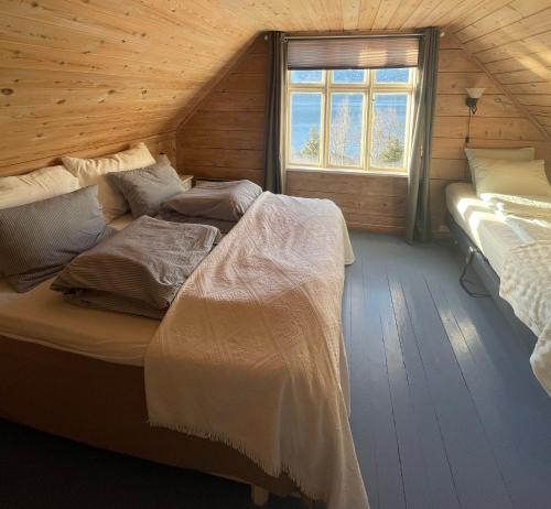 two beds in a wooden room with a window at Secluded Holiday Home, With private beach in Ålesund