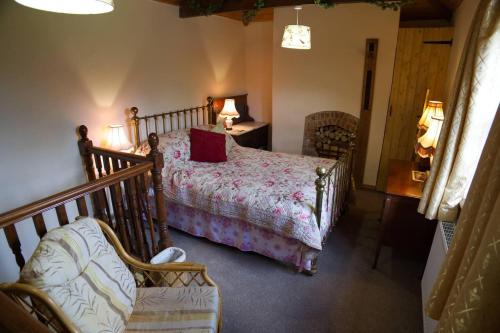 a bedroom with a bed and a chair in a room at Cosy secret cottage in a beautiful walled garden in Ryton