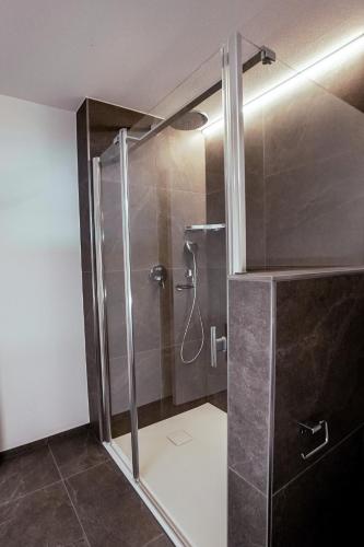 a shower with a glass door in a bathroom at Seehotel Baumgarten in Kehrsiten