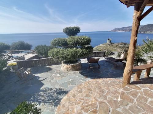 a patio with a tree and the ocean in the background at Logement de charme avec piscine privative in Pino