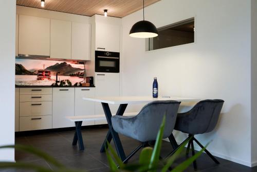 a kitchen with white cabinets and a table and chairs at Seehotel Baumgarten in Kehrsiten