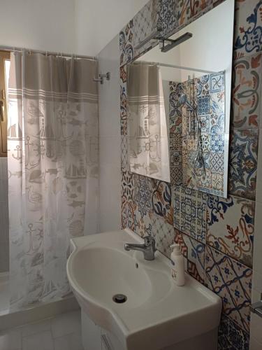 La salle de bains est pourvue d'un lavabo et d'un rideau de douche. dans l'établissement Soffio di Mediterraneo appartamento, à Trapani