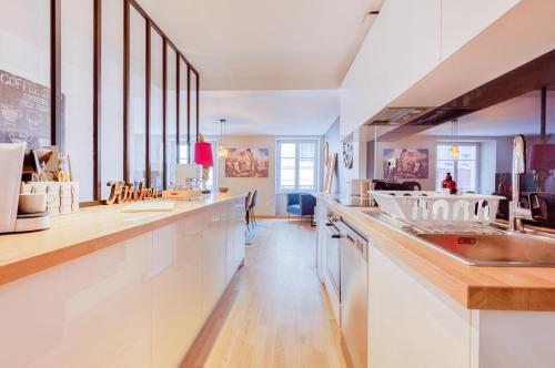 une cuisine avec des armoires blanches et un évier dans l'établissement Maison de l'Arsenal, à Mulhouse