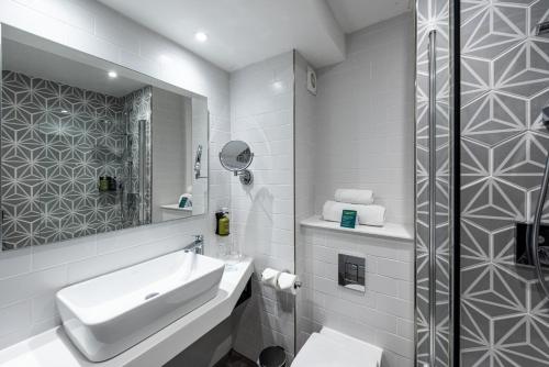 a white bathroom with a sink and a mirror at Holiday Inn - Manchester - Oldham by IHG in Manchester