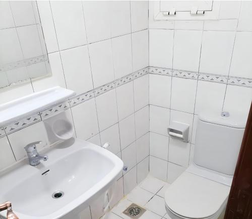 a white bathroom with a sink and a toilet at Corniche AD - For Males "Peaceful Bed Space" in Abu Dhabi