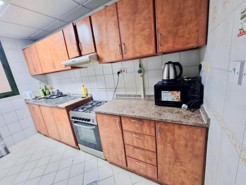 a small kitchen with wooden cabinets and a stove at Corniche Street - For Males "Peaceful Bed Space" in Abu Dhabi