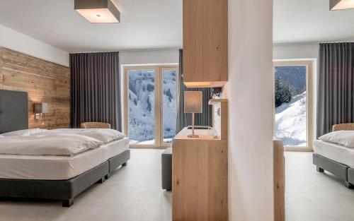 a bedroom with two beds and two windows at Mondschein Hotel & Chalet Ski-In Ski-Out Luxus am Arlberg in Stuben am Arlberg
