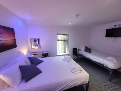 黑潭的住宿－Blackpool Resort Hotel，一间白色卧室,配有两张床和电视