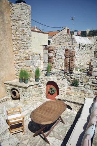 eine Terrasse mit einem Holztisch und einem Steinkamin in der Unterkunft Yi artistry 1-bedroom medieval holiday house in Kalamoti