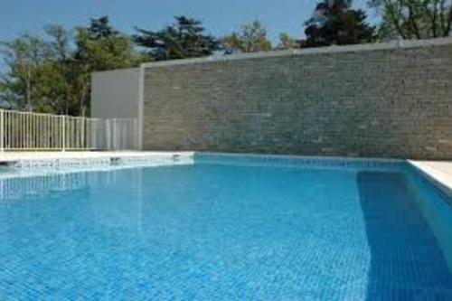 une grande piscine bleue à côté d'un mur en briques dans l'établissement Votre séjour cosy à Frejus!, à Fréjus