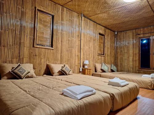 two beds in a room with wooden walls at คูณ-เนื่อง ฟาร์ม สเตย์ หัวหิน Koon & Nueang Farm Stay Hua Hin in Ban Bo Fai