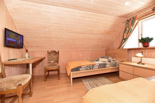 a room with two beds and a desk and a tv at Dalija in Druskininkai