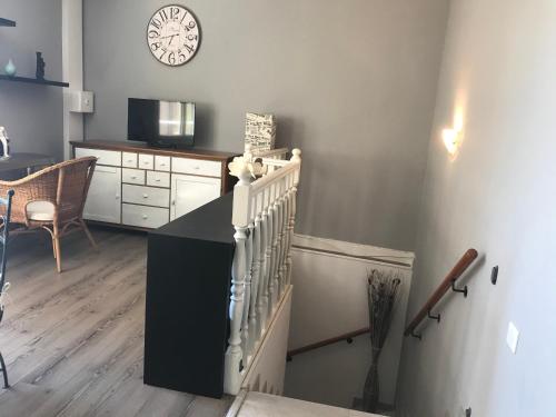 un salon avec un escalier et une horloge sur le mur dans l'établissement Appartement entier 3 pièces face au port, à Vallauris
