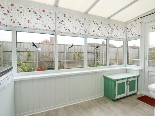 a kitchen with windows with butterflies on the curtains at 32 Queen Elizabeth Drive in Dersingham