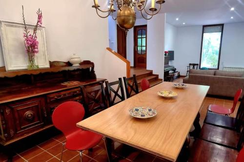 uma sala de jantar com uma mesa de madeira e cadeiras vermelhas em Casa MATRIA em Ponteareas