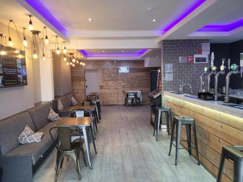 a restaurant with tables and a bar with purple lights at Blackpool Resort Hotel in Blackpool