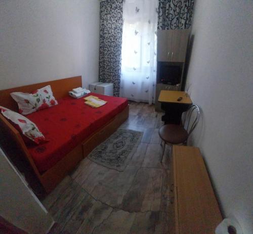 a small bedroom with a red bed and a desk at Garsoniera in Buzău