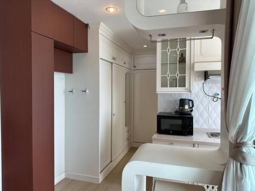 a kitchen with white cabinets and a black microwave at บ้านชายทะเล ที่พักติดทะเล ระยอง หาดแสงจันทร์ in Rayong
