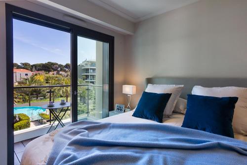um quarto com uma cama e uma grande janela em Parc du Cap Luxury Apartment em Antibes