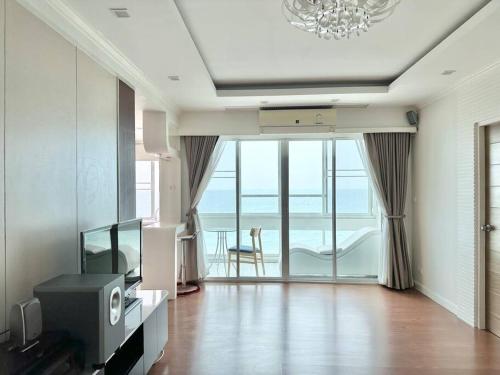 a living room with a television and a view of the ocean at บ้านชายทะเล ที่พักติดทะเล ระยอง หาดแสงจันทร์ in Rayong