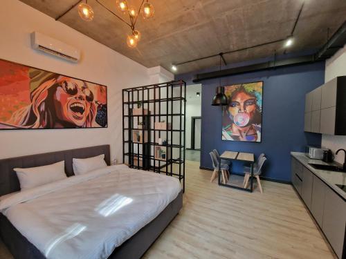 Apart Hotel LOFT في ألماتي: غرفة نوم بسرير كبير ومطبخ