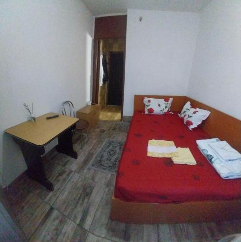 a bedroom with a red bed and a wooden table at Garsoniera in Buzău