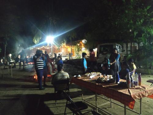 a group of people standing around a table at night at Holiyday in VGF Farm House in Dānishpet