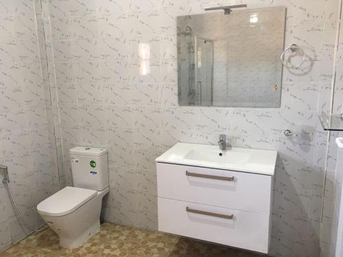ein Badezimmer mit Toilette, Waschbecken und Spiegel in der Unterkunft KALSA Residence in Sukuta