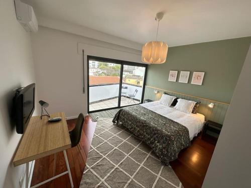 a bedroom with a bed and a desk and a television at Duplex 8 in Ribeira Grande