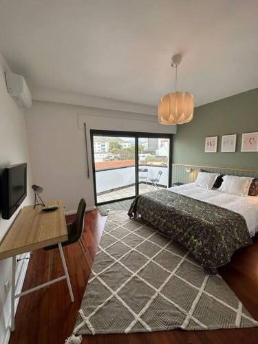a bedroom with a bed and a table and a window at Duplex 8 in Ribeira Grande