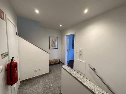 a hallway with a red fire extinguisher in a building at Conforto, espaço e localização in Ribeira Grande