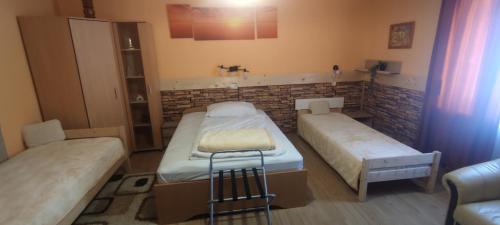een kamer met 2 bedden en een stoel. bij Krisztina Apartman in Nagykanizsa