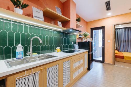 cocina con fregadero y pared de azulejos verdes en Ecopark QV Homestay NA, en HÆ°ng YÃªn